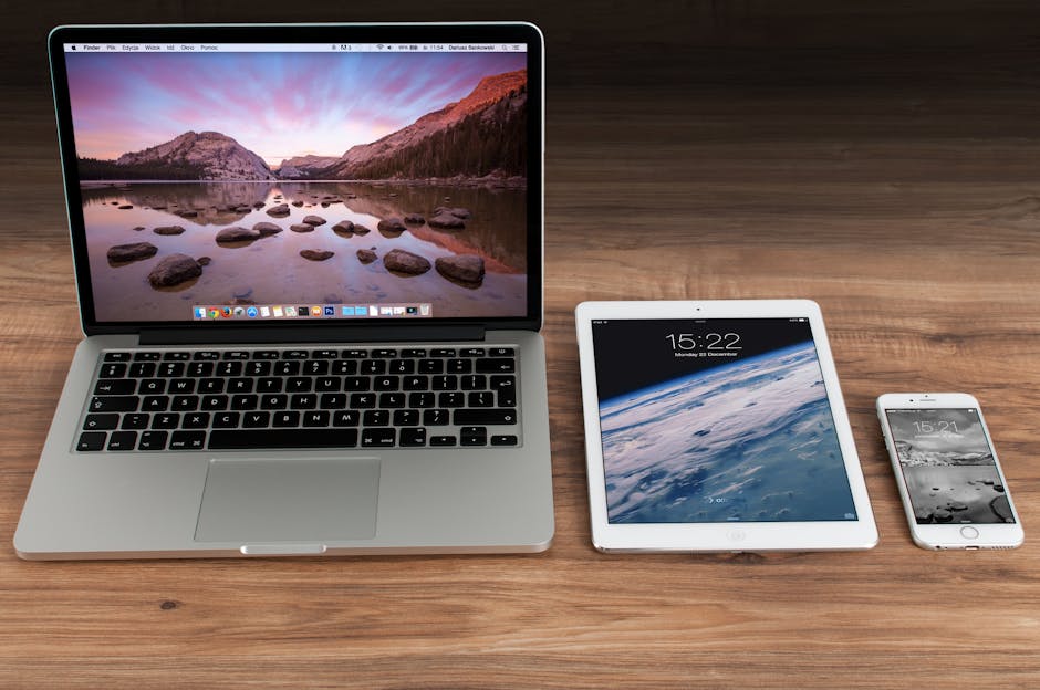 Modern workspace showcasing Apple laptop, tablet, and smartphone on a wooden desk